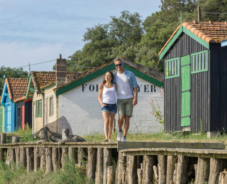 Région, Île d\'Oléron, couple qui se promène à côté de cabanes de pêcheurs